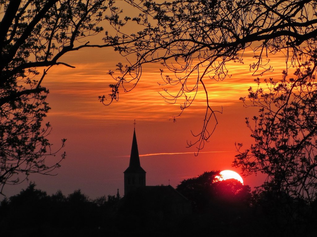 Die untergehende Sonne am Abend des 18.05.2013 in Stolberg-Breinig mit dem Kirchturm von St. Barbara.