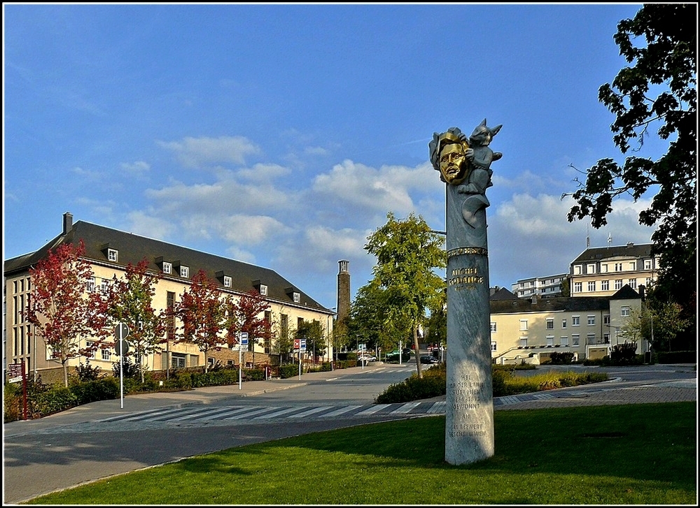 Mitten in der Ortschaft, zwischen Wiltz und Niederwiltz, entstand ein Denkmal zu Ehren des luxemburgischen Nationaldichters Michel Rodange. Hier in Wiltz, und zwar genauer gesagt „op der Lann – am Haus a Schumachich“,  schrieb dieser zwischen 1866 und 1872 sein erstes Werk in luxemburgischer Sprache: „DE REENERT – de Fuuss am Frack an a Maansgrisst“. Das Monument fr Michel Rodange und sein Werk „Reenert“ ist eine 4,40 M hohe Sule aus Bardiglietto-Marmor. Sie steht unten im Schulberg, nur ein paar Meter von dem Haus entfernt, wo unser Nationalepos geschrieben wurde. Hier http://de.wikipedia.org/wiki/Michel_Rodange kann man einen Auszug aus dem  Reenert  in luxemburgischer Sprache anhren. 04.09.2010 (Hans)