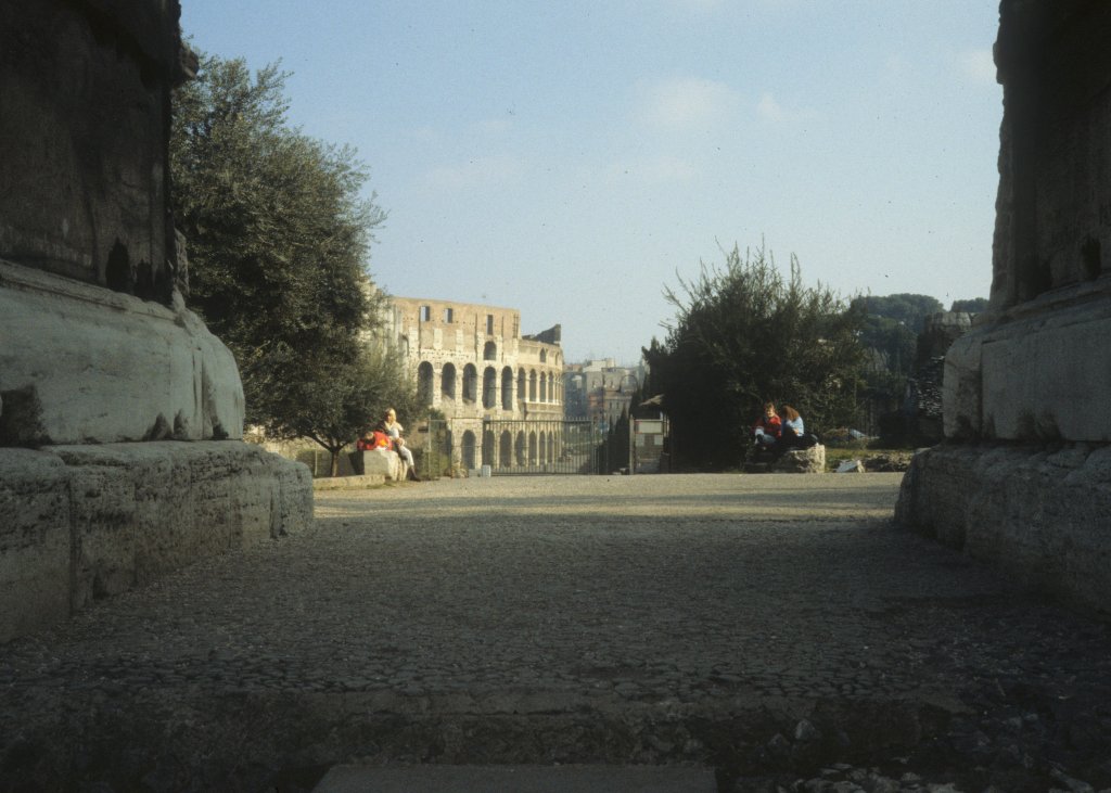 Roma / Rom im Februar 1989: Ein Teil des Kolosseums durch den Titus-Bogen gesehen.