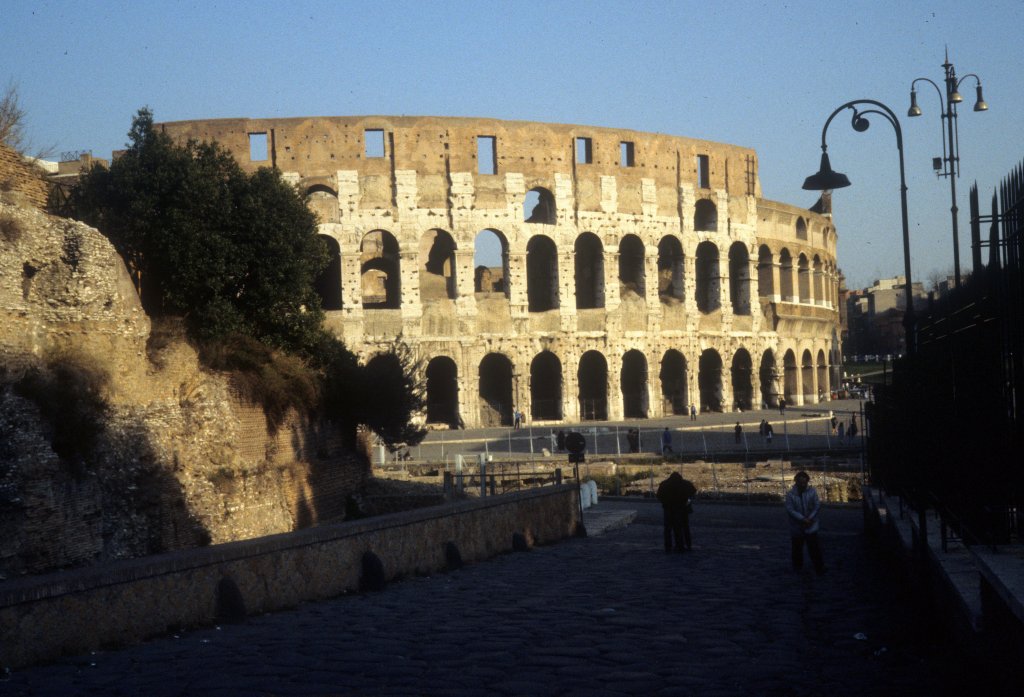 Roma / Rom im Februar 1989: Den Namen Colosseum, deutsch Kolosseum, bekam das Amphitheater erst im Mittelalter. Es wurde nach einer bronzernen Kolossalstatue von Nero benannt, die ursprnglich an der Stelle stand, wo Kaiser Hadrian spter das Templum Veneris et Romae, den Tempel der Venus und Roma, errichten liess. 