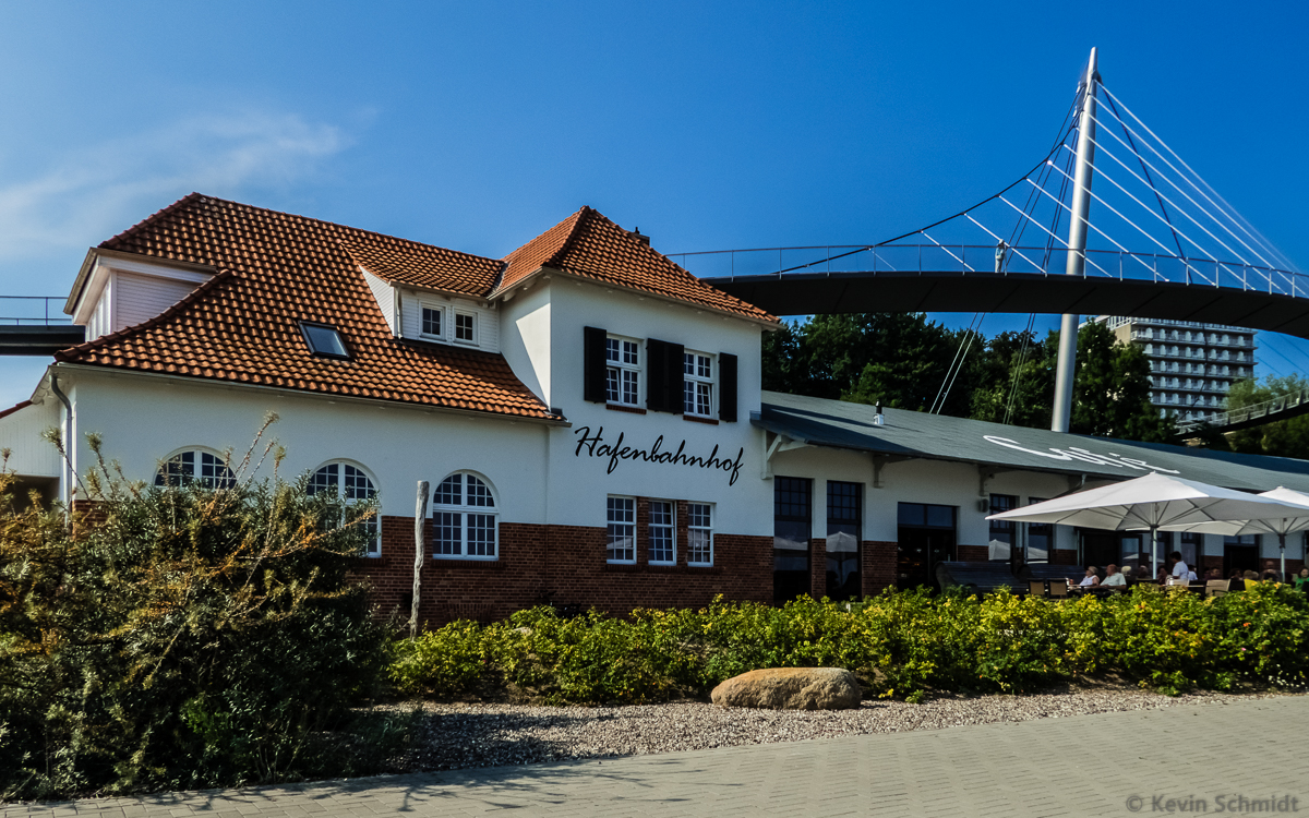Das Gebude des ehemaligen Hafenbahnhofs in Sassnitz wird heute gastronomisch genutzt. Rechts im Bild ist die imposante Hngebrcke vom Zentrum der Stadt zum alten Hafengelnde zu sehen. (26.07.2014)