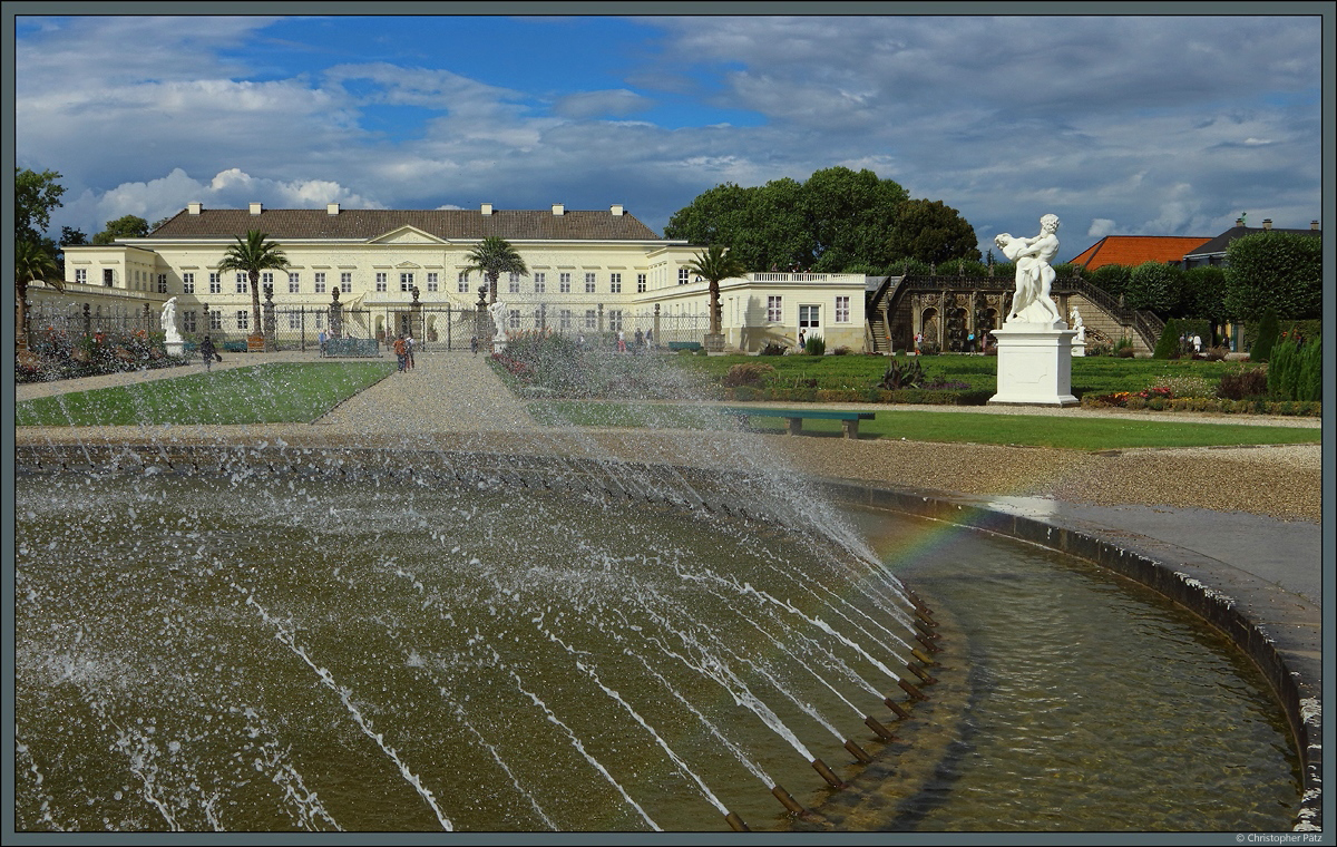 Das Zentrum des nrdlichen Gartenbereichs der Herrenhuser Grten bildet die Glockenfontne, die hier einen kleinen Regenbogen erzeugt. Im Hintergrund sind das Schloss Herrenhausen sowie die rechts daneben liegende groe Kaskade zu sehen. (11.08.2018)