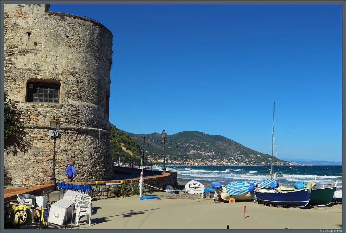 Der aus dem 16. Jahrhundert stammende Torrione del Cavallo, eines der Wahrzeichen des Kstenortes Laigueglia, wacht ber die auf dem Strand liegenden, bunten Fischerboote. Im Hintergrund ist die Stadt Alassio zu sehen, die unmittelbar nrdlich von Laigueglia liegt. (25.09.2018)