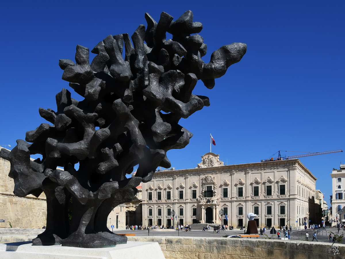  Die Flamme, die niemals sterben wird  ist ein 2017 aufgestelltes Kunstwerk in Valletta, dahinter der in den 1740er-Jahren im barocken Stil erbaute jetzige Amtssitz des Premierministers von Malta. (Oktober 2017)