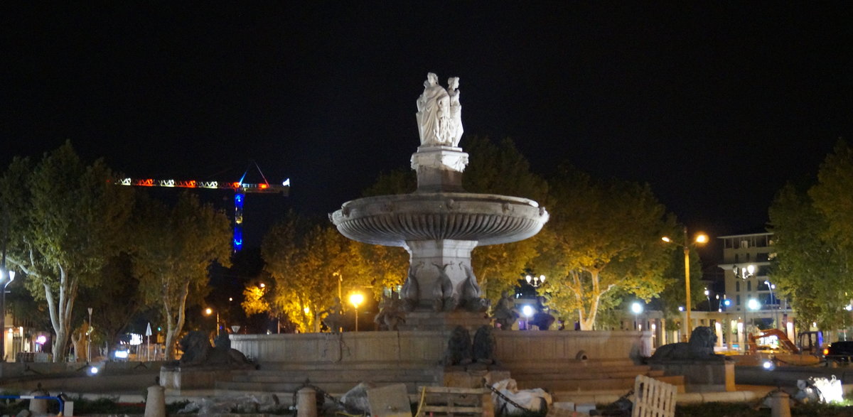 Die Fontaine de la Rotonde (historischer Springbrunnen aus den 1860er-Jahren) in Aix-en-Provence. Im Hintergrund leuchtet ein Baukran in den franzsischen Nationalfarben; 09.09.2018.