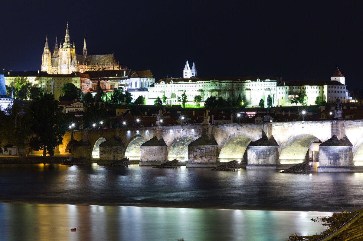 Die Prager Burg in der Nacht vom 26. auf den 27.08.2021. Im Vordergrund fliet die Moldau unter der Karlsbrcke hindurch. 