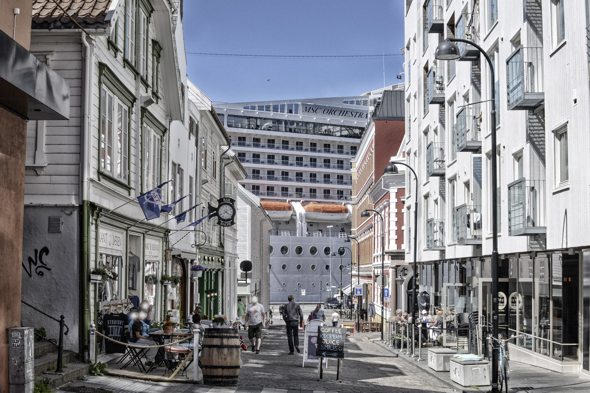 Eine Aufnahme von der Strae vre Holmgate in Stavanger. Im Hintergrund ist ein Teil des riesigen Kreuzfahrtschiffes MSC Orchestra zu sehen. Aufnahme: 3. Juli 2018.