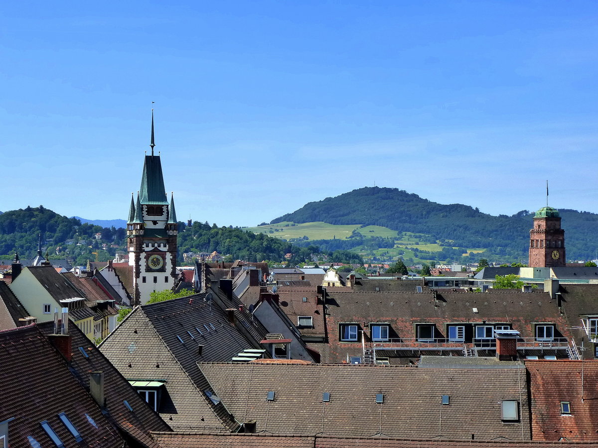 Freiburg, Blick von einer Dachterrasse an der Kaiser-Joseph-Strae ber die Dcher der Altstadt zum 645m hohen Schnberg, rechts der Universittsturm, links das Martinstor, Juni 2014 