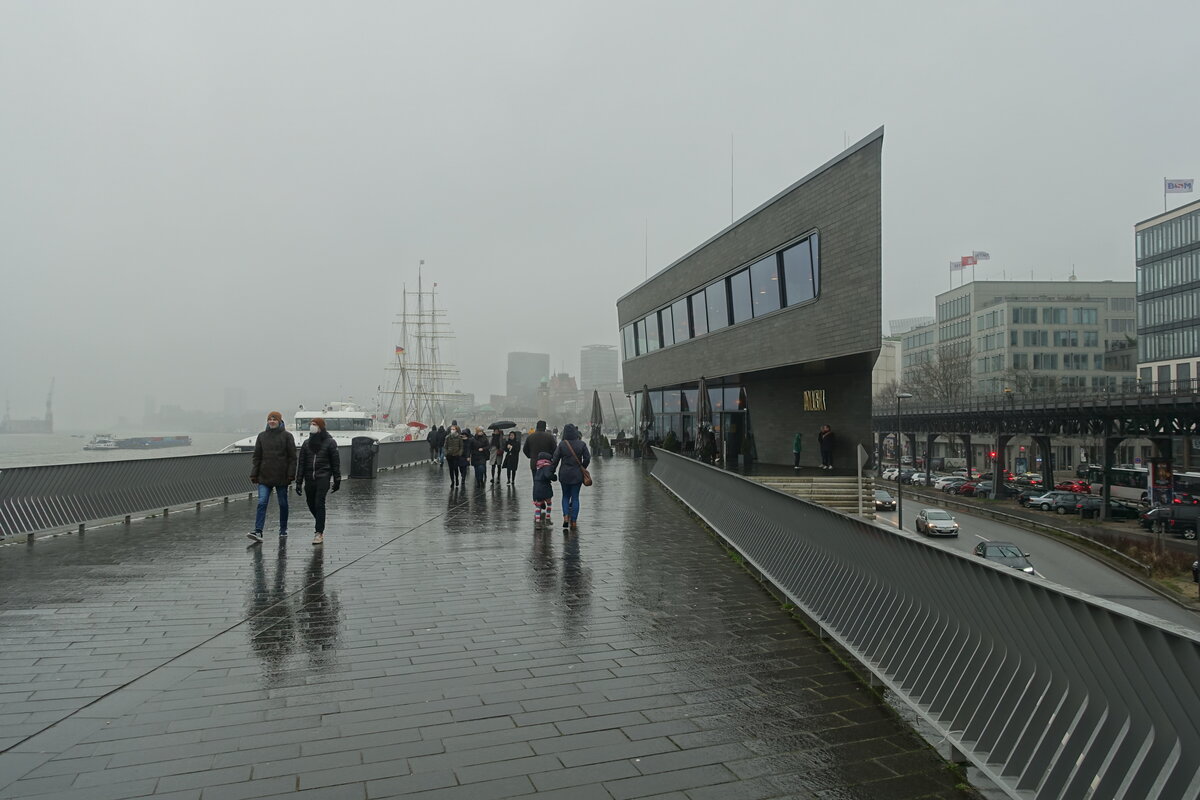 Hamburg am 16.1.2022: trbes Wetter mit leichtem ganztgigen Sprhregen, relativ viele Menschen trotzen dem Wetter, Jan-Fedder-Promenade (Hochwasserschutzanlage) Richtung Landungsbrcken gesehen  /