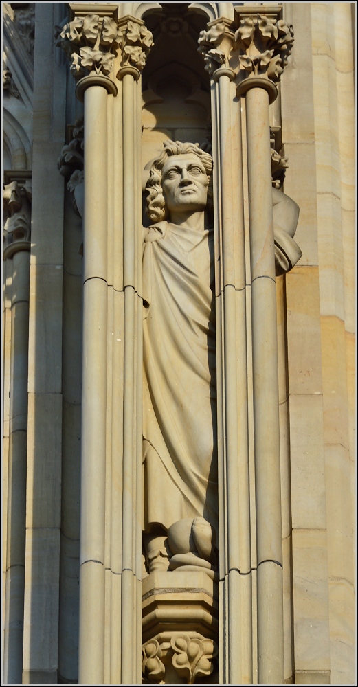Kunst am Klner Dom - Heiligenfiguren. Hinter den gotischen Sulen schaut die Figur nicht nach gotischem Stil aus. Frhjahr 2014.