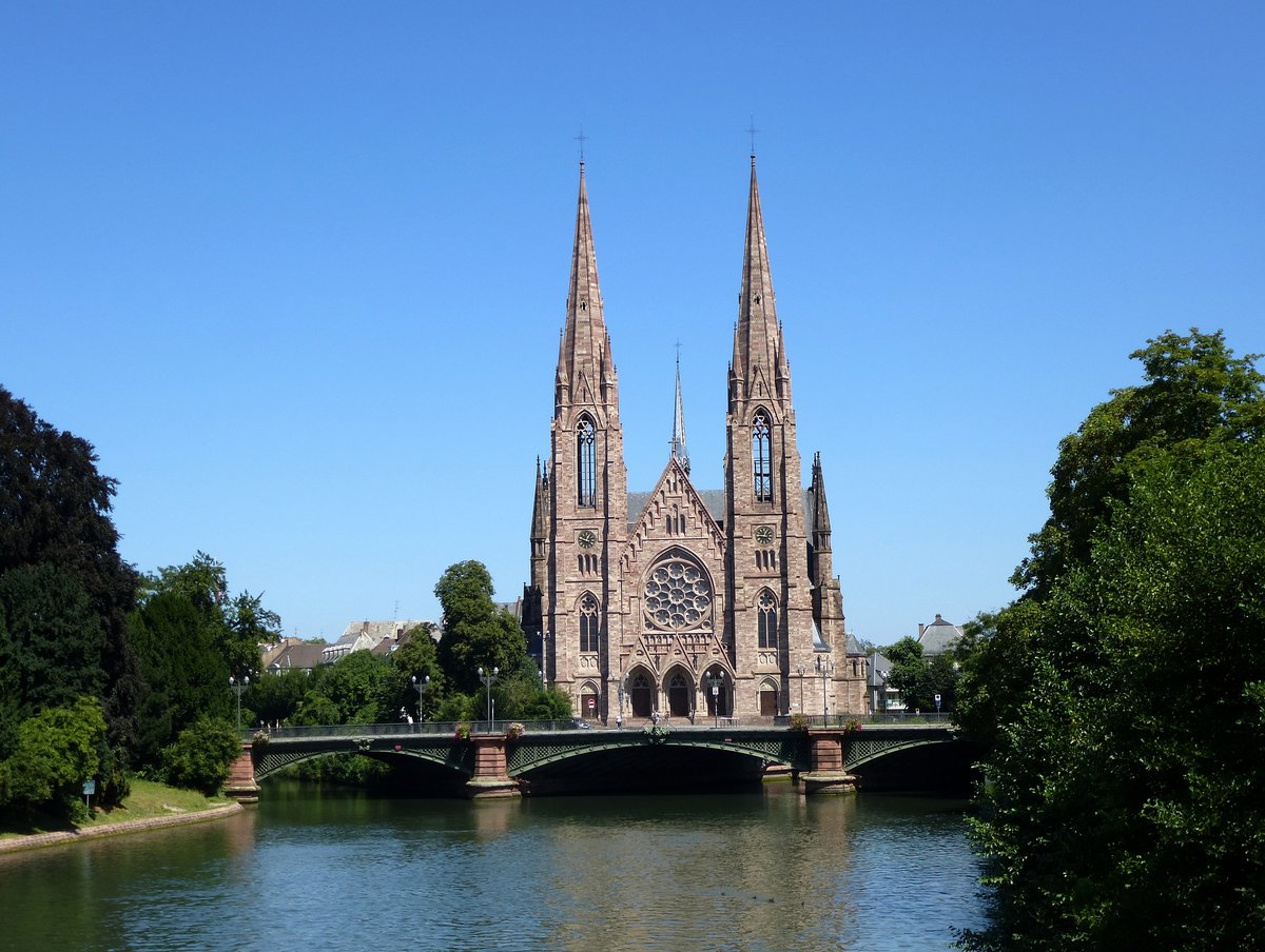 Straburg, die evangelische Kirche St.Paul, als Garnisionskirche 1892-97 im neugotischen Stil erbaut, mit den zwei markanten 76m hohen Glockentrmen, davor die 1892 erbaute Brcke Pont d'Auvergne ber die Ill, Aug.2016