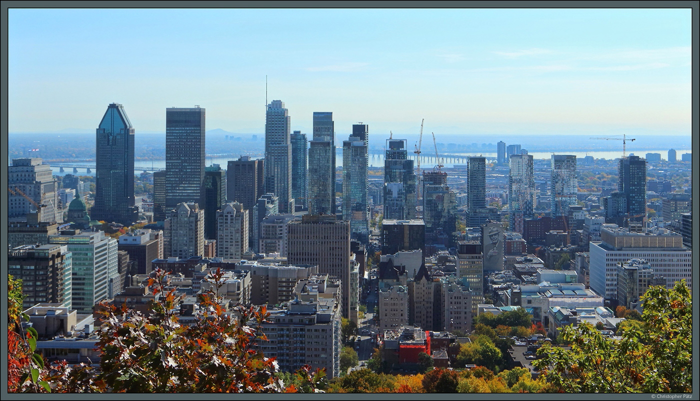 Blick vom Mont Royal auf den sdlichen Teil der Downtown von Montreal: Links sticht der Broturm Atrium Le 1000 hervor. Neben modernen Konstruktionen aus Stahl und Glas sind auch einige ltere Hochhuser zu sehen, so in Bildmitte im Vordergrund das Le Chteau Apartments aus den 1920er-Jahren mit seinen Trmen. (11.10.2022) 