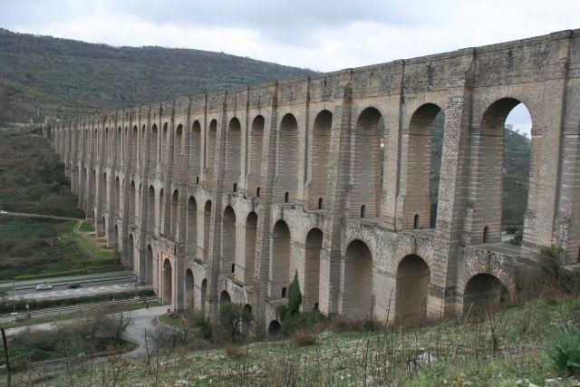 Das Carolino-Aqudukt gehrt mit zum Bauumfang des Kniglichen Palastes von Caserta und wurde ebenfalls vom Architekten Luigi Vanvitelli entwurfen. Daher trgt es auch den Beinamen  Acquedotto di Vanvitelli . Das Aqudukt ist Bestandteil einer 38km langen Wasserleitung, mit der Caserta und vor allem der Palast mit Wasser versorgt wurde.