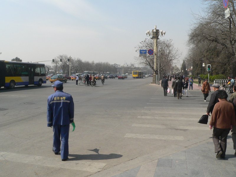 Ein Traffic Assistent (in blau, links) sorgt dafr, dass die Fugnger die groe Strae nur bei Grn berqueren. Die Strae fhrt direkt an der verbotenen Stadt vorbei. April 2006