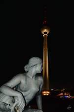 Eine der Nymphen des Neptunbrunnens  posiert  vor dem Fernsehturm in Berlin.