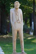 Am Fusse der Skulptur in Koserow steht die Infotafel mit Titel und Knstler:  Urlauber im Ostseebad Koserow von  Volker Sesselmann .