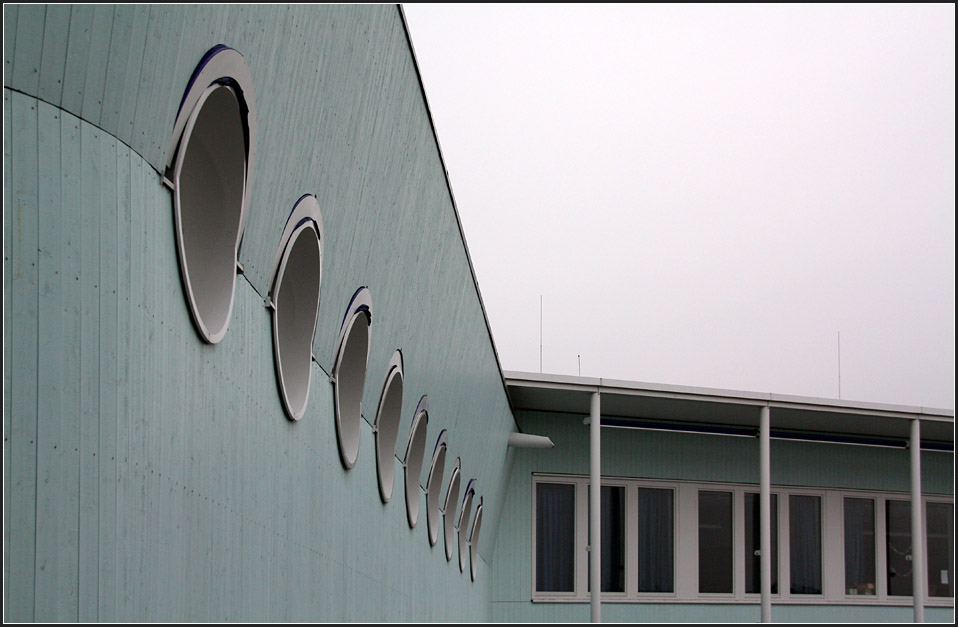 . Das Lehrerzimmer mit seinen Bullaugen wirkt wie eine Kommandobrcke. Die Assoziation mit Augen wird bei ausgefahrenem Sonnenschutz noch verstrkt, die blauen gerundeten Markisen wirken wie Augenlider. 05.03.2011 (Matthias)