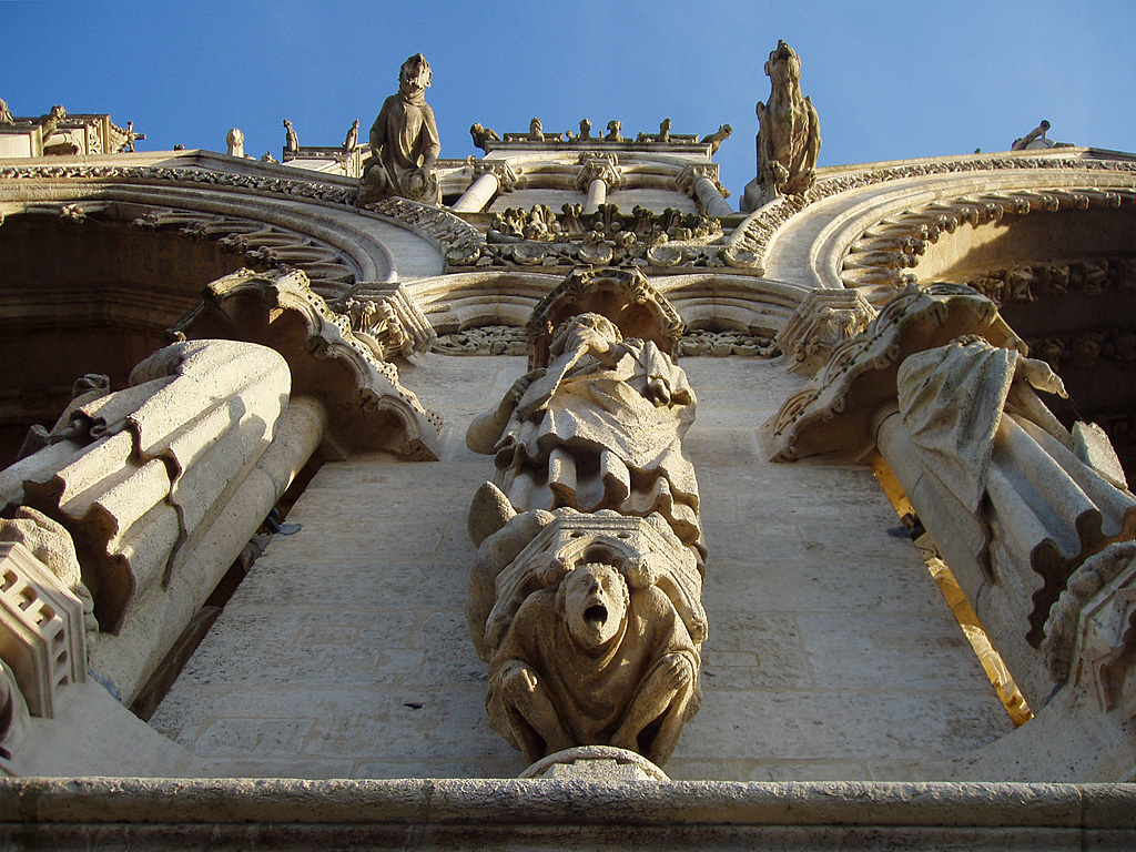 Amiens, Kathedrale Notre Dame. Blick von unten auf Statuen und Wasserspeier des Pfeilers zwischen Portal des hl. Firmin und Mittelportal der Westfassade. Aufnahme vom 14. Jan. 2006, 15:22