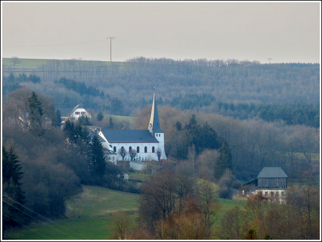 Blick vom Aussichtspunkt  Geeselee  in Lellingen nach Pintsch. Die Kirche von Pintsch war im Mittelalter eine der wichtigsten Kirchen des slings, eine der sogenannten Mutterkirchen. Der mchtige Glockenturm stammt aus dem 11. Jahrhundert und ist neben der Sakristei, der lteste Teil des Gebudes. Whrend der Ardennenoffensive 1944/45 wurde das Gotteshaus stark beschdigt, doch schon 1949 war es wieder aufgebaut. 20.03.2012 (Jeanny)