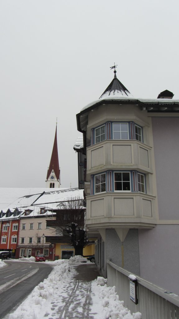 Blick ber Brixlegg. Hier die Zubringerstrae zum Ortskern mit einem interessant gebauten Brogebude. Im Hintergrund der Kirchturm. (8.1.2012)