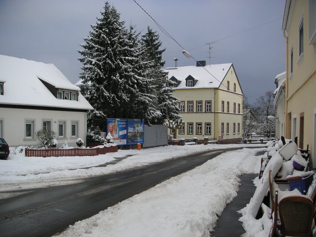 Das Foto zeigt den Ortskern von Saarbrcken Ensheim. Die Aufnahme des Fotos war am 01.02.2010. Das Gebude hinter den Tannen ist die ehemalige Grundschule von Ensheim.