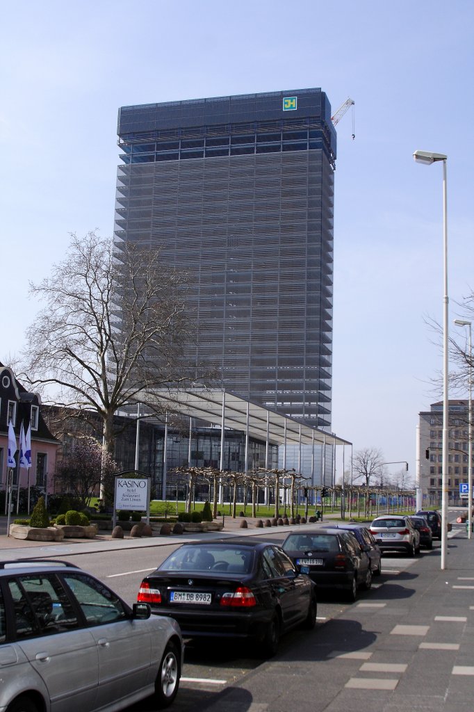 Der Abriss des Bayer-Hochhauses in Leverkusen hat begonnen! Das Bild zeigt das bereits entkernte, 122 Meter und 31 Stockwerke hohe Gebude, kurz nach Beginn des Rckbaus. Errichtet wurde es 1960-63 in Stahlskelettbauweise nach Plnen der Architekten Hentrich, Pettschnigg & Partner im Avantgarde-Stil. Einst Sitz der Hauptverwaltung des Bayer-Konzerns und eines der Wahrzeichen der Stadt Leverkusen, 1999 zum 100-jhrigen Aspirin-Jubilum in Form einer riesigen Aspirinschachtel verhllt, sollte es nach seiner Auerdienststellung im Zuge der Fertigstellung einer neuen Konzernzentrale (im Bild direkt vor dem Hochhaus), in eine aus zahllosen LED`s bestehende Medienfassade umgebaut werden. Nachdem dieses Vorhaben aufgrund technischer Probleme scheiterte, entschied man sich endgltig fr den Abriss. Das Gebude wird nun in wenigen Monaten der Vergangenheit angehren und Geschichte sein.
Die Aufnahme entstand am 24.03.2012 von der Kaiser-Wilhelm-Allee aus.