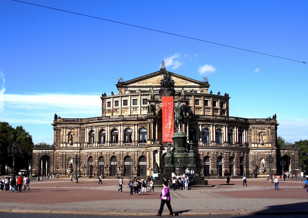 Die berhmte Semper-Oper am Theaterplatz in Dresden. Das ursprngliche (heute nicht mehr vorhandene) Gebude wurde von 1838-1841 durch Baumeister Gottfried Semper (erschuf auch das Wiener Hoftheater) als Neues Knigliches Hoftheater in den Formen der italienischen Frhrenaissance erbaut und am 13.04.1841 erffnet. Im Jahr 1869 wurde es durch einen verheerenden Brand vollstndig zerstrt. Auf Wunsch der Dresdener Bevlkerung entwarf Gottfried Semper ein neues Bauwerk, welches unter Fhrung seinen Sohnes Manfred Semper in den Jahren von 1871-1878 erbaut wurde und auch den heutigen Bau darstellt. In der Nacht vom 13. zum 14.02.1945 fiel die Semper-Oper im Zweiten Weltkrieg durch alliierte Luftstreitkrfte dem grten, jemals geflogenen, konventionellen Bombenangriff zum Opfer und wurde dabei bis auf die Grundmauern zerstrt!
Bereits zu DDR-Zeiten wurde der Wiederaufbau unter Leitung des Chefarchitekten Wolfgang Hnsch als Prestige-Objekt in Angriff genommen und in den Jahren von 1977-1985 unter gewaltigem Aufwand fertiggestellt. Seither gehrt die Semper-Oper wieder zu den bekanntesten Opernhusern weltweit.
(Aufnahme vom 06.10.2011)