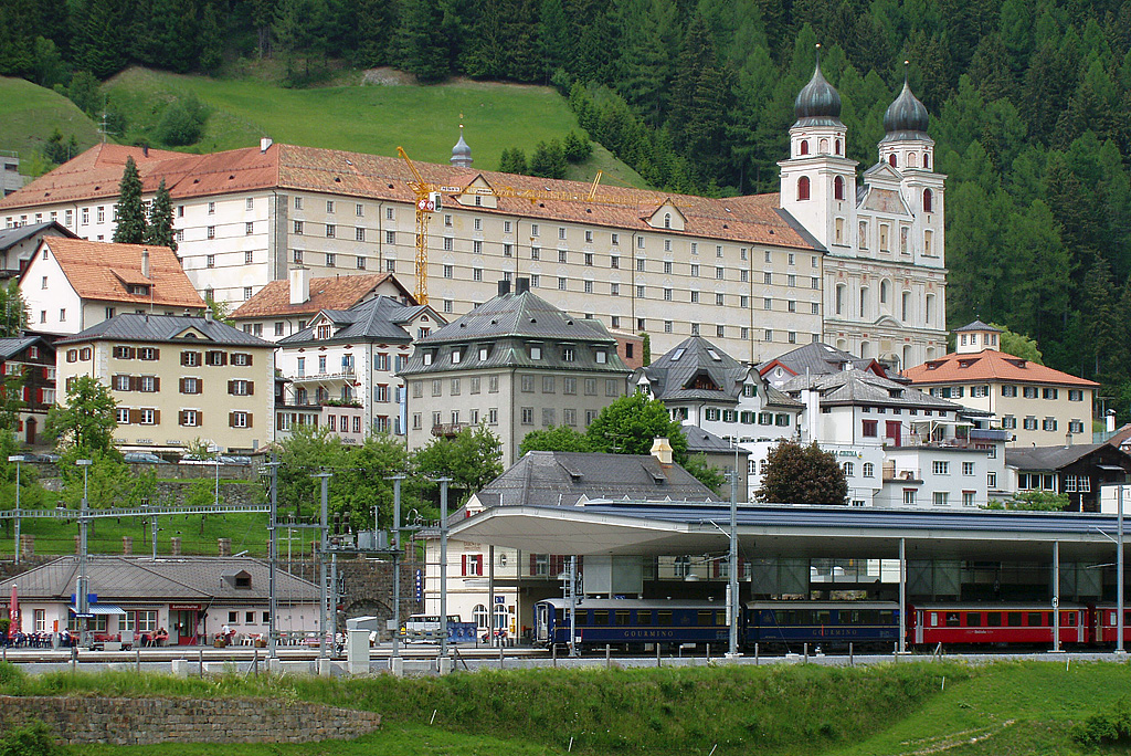 Disentis, Klosterkirche St. Martin. Grndung um 720. Unter Abt Adalbert III de Funs in Barock neu erbaut nach Projekt von Caspar Moosbrugger, Rohbau vollendet 1704. Aufnahme Gesamtanlage mit Doppelturm-Hauptfassade und Bahnhof von Sden, 30. Mai 2003.