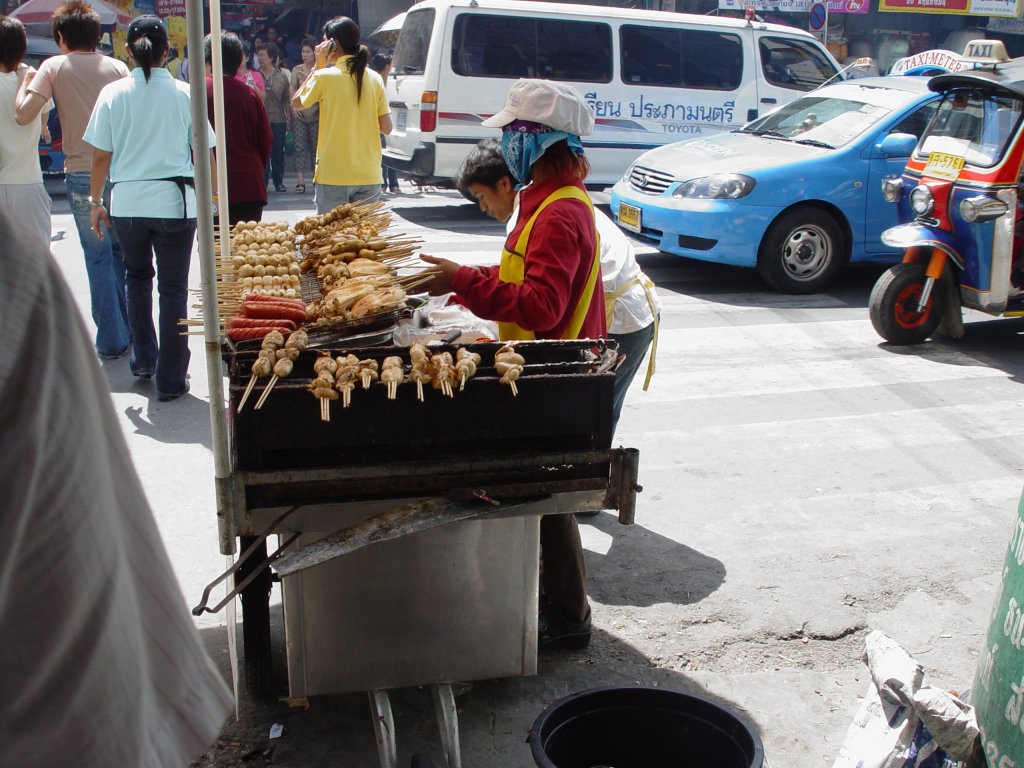 Eine der vielen  Garkchen  in Bangkok bietet hier am 28.05.2006 allerlei am Spie an. Gegrillte Wrstchen, Hhnchenteile, Fleischbllchen und etliches mehr. Der Abfall befindet sich unmitelbar neben dem Verkaufsstand, eine Plastiktonne.