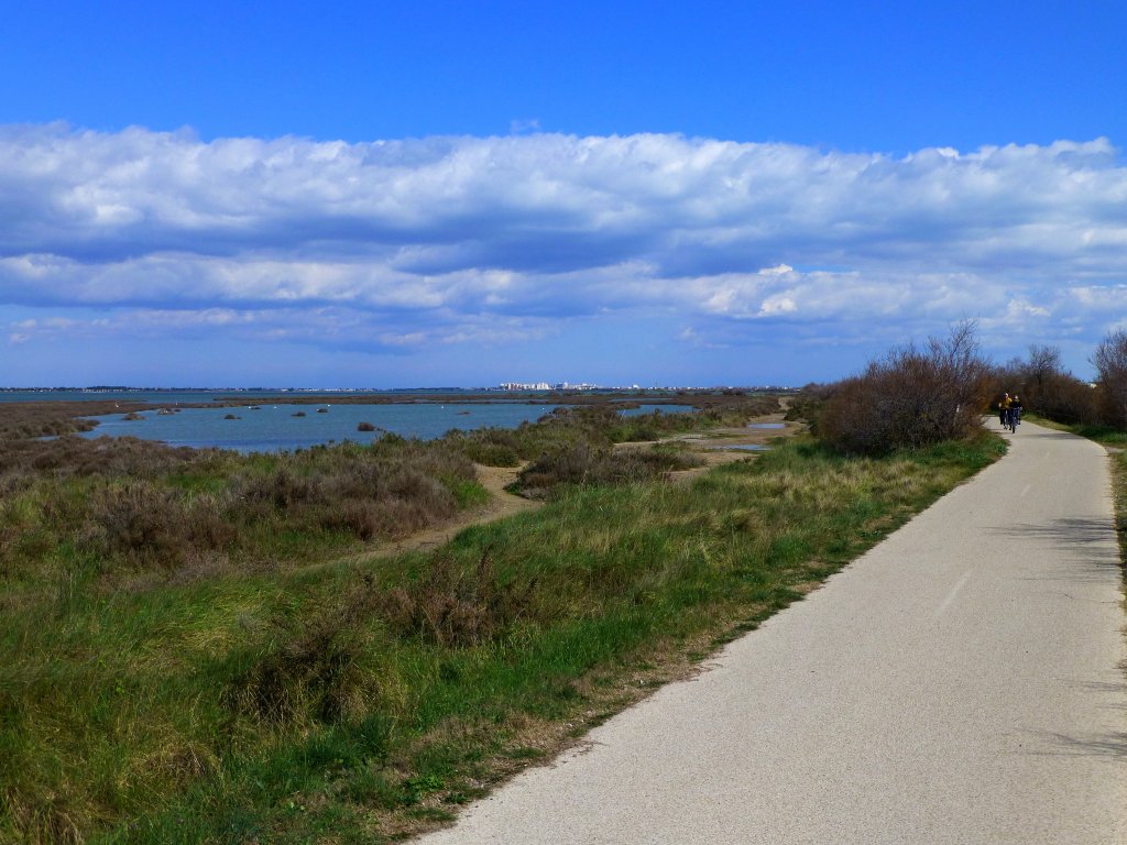 Frankreich, Languedoc, Radweg von Lattes nach Palavas am Mittelmeer auf der Trasse der ehemaligen Bahnstrecke Montpellier-Palavas. Blick auf die Weiher und den Radweg von Lattes aus in Richtung Palavas. 25.03.2013