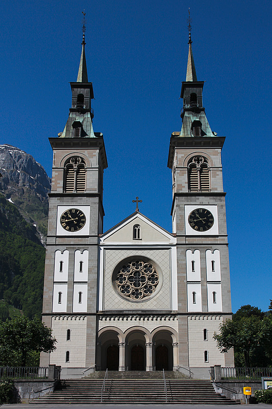 Glarus, Stadtkirche. Doppelturmfassade von Osten. Lisene und Rundbogenfriese lehnen sich an die Romanik, Rosenfenster mit Vierpass-Masswerke mit gotischem Vorbild. Aufnahme vom 05. Juni 2010, 10:45