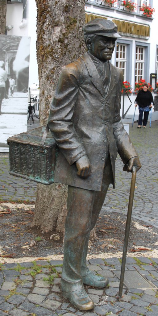 Hier hat der Bildhauer Klaus Gehlen aus Monschau-Mtzenich dem Monschauer Original  Maaens Pulche  (1856-1940) ein Denkmal geschaffen. Die lebensgroe Figur erinnert an einen reisenden Kaufmann, der Kurzwaren im Monschauer Land an der Haustre seiner Kunden anbot. (07.09.2011)