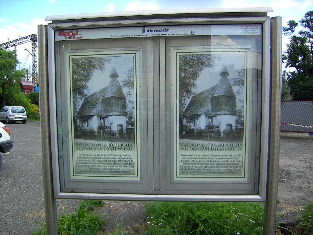 Informationstafel auf der Rckseite des Bahnhofes Kandrzin-Cosel (Kedzierzyn-Kozle) in Oberschlesien im Sommer 2010 (mittlerweile verschmiert). An der Stelle des hier befindlichen Parkplatzes stand einst eine Holzkirche mit Friedhof. Die Holzkirche wurde noch zu deutscher Zeit in den Scheitniger Park (Park Szczytnicki) nach Breslau (Wroclaw) versetzt und ist dort heute Touristenattraktion.