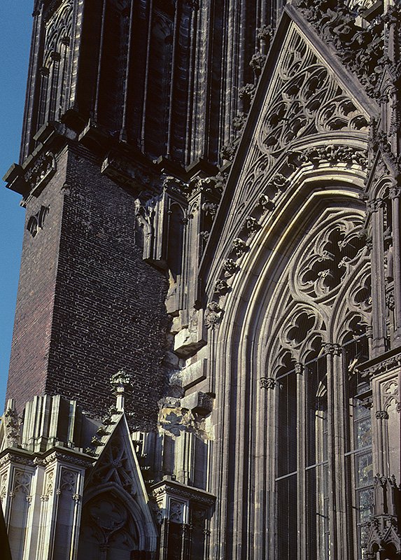 Kln, Hohe Domkirche, Nordturm/Westfassade. Pfeiler (links) wurde nach schweren Schden des 2. Weltkriegs mit Backsteinmauern gesichert. Zustand von Aug. 2002, mittlerweile restauriert. HQ-Scan ab Dia.