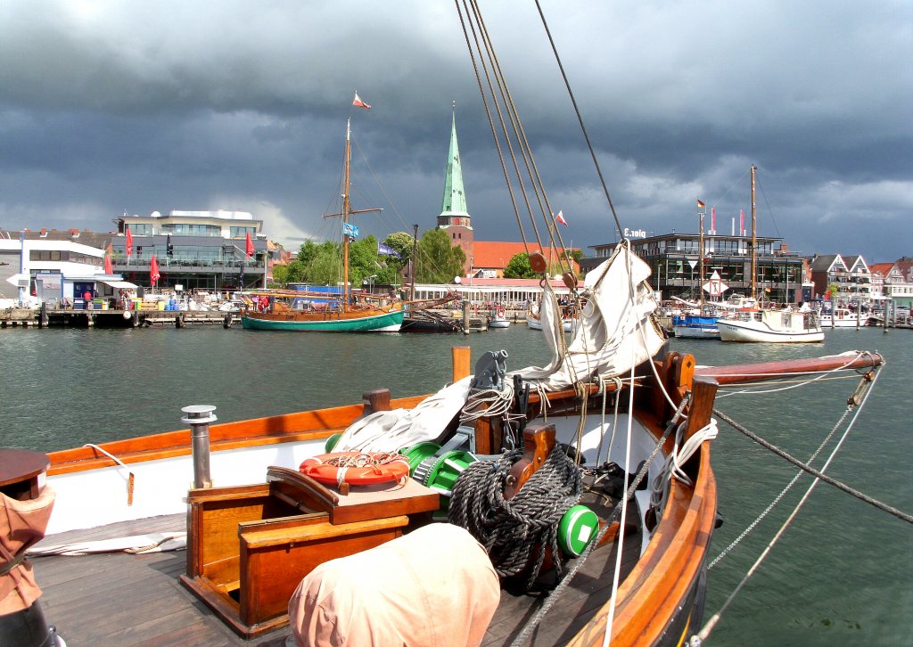 Lbeck-Travemnde. Blick ber einen Oldtimer zum Fischereihafen-Ufer mit der St. Lorenzkirche vor den Regenwolken... Aufgenommen: 15.5.2011