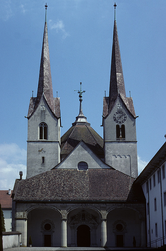 Muri AG, ehemalige Klosterkirche, Westeingang (unten: Renaissance) mit Doppelturmfassade. Komplexe Anlage mit zahlreichen Vernderungen. Unterer Teil Sdturm (r.) romanischen Ursprungs. Oberbau Nordturm sowie der beiden Spitzhelme 1558. Aufnahme vor der Aussenrestauration. Juli 1994, HQ-Scan ab Dia.