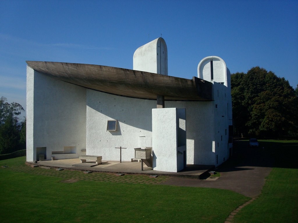 Wallfahrtskirche in Ronchamp / Frankreich,
hier ist die Ostseite zu sehen, sie bildet mit dem berhngenden Dach eine Freiluftkapelle mit Freialtar und Auenkanzel, die Nordseite mit dem kleineren Doppelturm liegt im Schatten,
Sept.2010