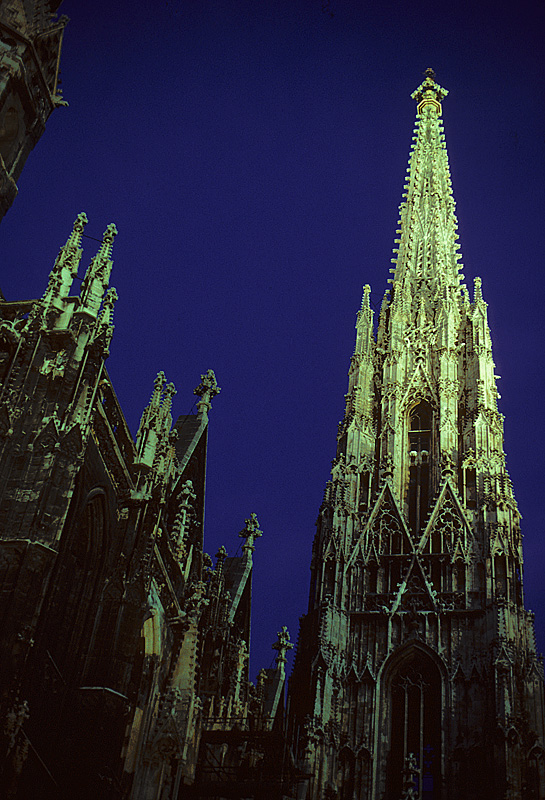 Wien, Stephansdom (Domkirche St. Stephan), Nachtbeleuchtung. Wahrzeichen Wiens und Meisterwerk der Sptgotik. Fragment des sdlichen Langhauses (l.) sowie Sdturm (r.), dessen Bau bereits im Mittelalter (1433) abgeschlossen werden konnte. Er ist 136.4 m hoch und steht isoliert auf Fundamenten von nur 4 m Tiefe (vgl. Klner Dom: bis 17 m / N.D. Amiens: 7-9 m). Aufnahme Richtung Osten, Juli 1986, HQ-Scan ab Dia.