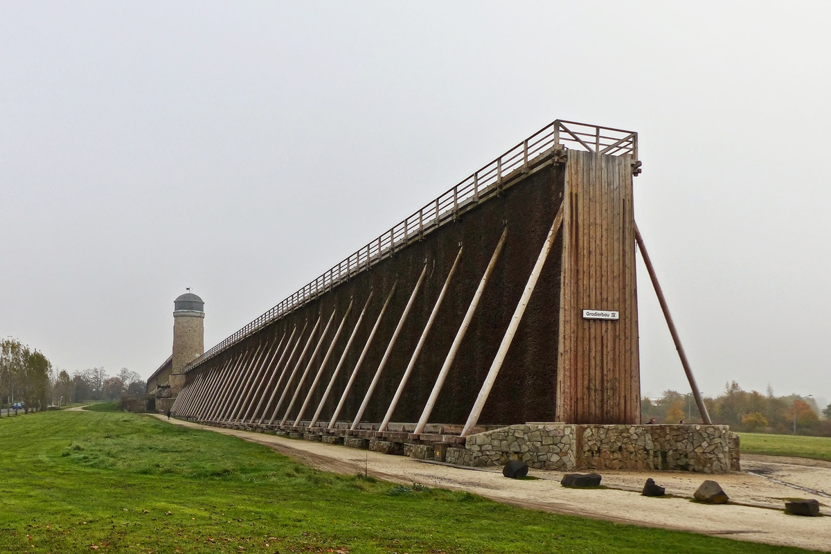 . Bad Nauheim (Wetterau) - Die Gradierbauten IV/V, die sogenannte Lange Wand mit dem Windmhlenturm. 01.11.2014 (Jeanny)

Ein Gradierwerk ist eine Anlage zur Salzgewinnung. Sie besteht aus einem Holzgerst, das mit Reisigbndeln (vorwiegend Schwarzdorn) verfllt ist. Das Verb  gradieren  bedeutet  einen Stoff in einem Medium konzentrieren . Im Falle eines Gradierwerks wird der Salzgehalt im Wasser erhht, indem Sole durch das Reisig hindurchgeleitet wird, wobei auf natrliche Weise Wasser verdunstet. Auerdem lagern sich Verunreinigungen der Sole an den Dornen ab; dadurch wird die Qualitt des erzeugten Salzes erhht.