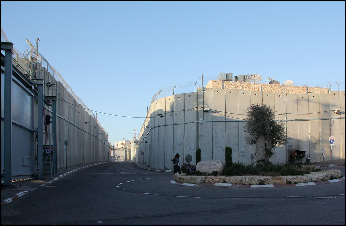 . Bethlehem, jenseits von Weihnachten -

Auf der anderen Seite der Mauer. Rechts ber der Mauer kann man das Dach des von drei Seiten von der Mauer umschlossenen Hauses erkennen, siehe anderes Foto. Links die Zufahrtstrae zum Grab von Rahel, die auf beiden Seiten von der Mauer umgeben ist, dahinter ist jeweils palstinensisches Gebiet. Hereinfahren kann man hier nur nach Passieren eines militrischen Checkpoints. Blickrichtung Norden.

27.03.2014 (Matthias)