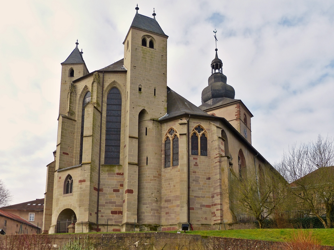 . Bouzonville - Die ehemalige Klosterkirche Heilig Kreuz (Sainte Croix) in Bouzonville (deutsch Busendorf, lothringisch Busendroff) im Dpartement Moselle in der Region Lothringen. 03.04.2015 (Hans)

Die Kirche ist eine querhauslose gotische Pseudo-Basilika mit offener Vorhalle. Der Turm erhielt in der Barockzeit eine welsche Haube. Das Chorgesthl mit figrlichen Schnitzereien entstammt der Barockzeit. Der Chorabschluss der Kirche verfgt ber zwei fr Lothringen typische Chorflankentrme. Das Mittelschiff ist 17 m hoch, die Seitenschiffe erreichen eine Hhe von 10 m.