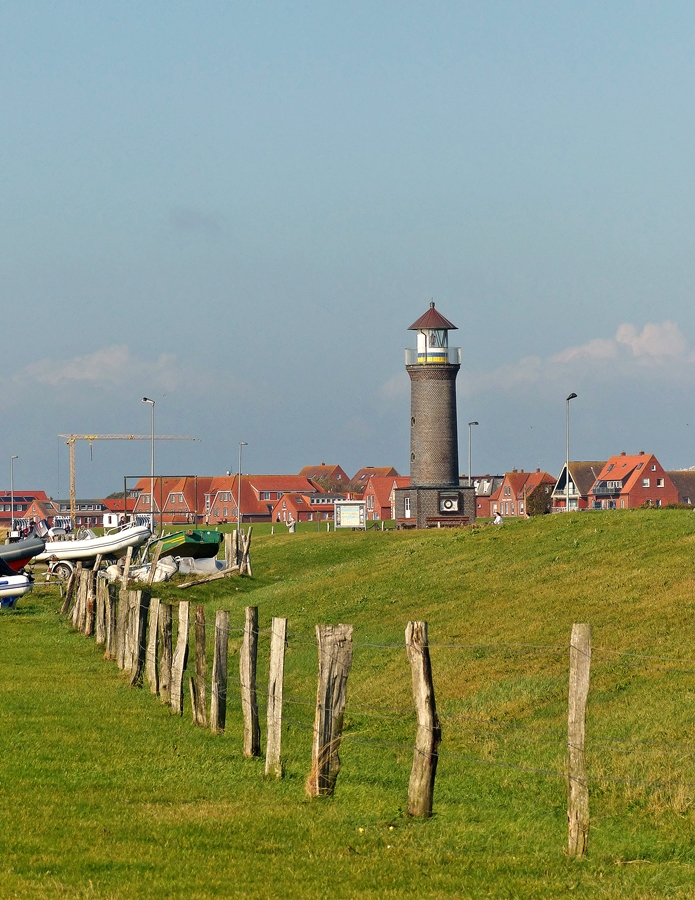 . Juist - Der Leuchtturm vom Yachthafen aus gesehen. 10.10.2014 (Jeanny)

Ursprnglich besa Juist keinen eigenen Leuchtturm. Die Leuchtfeuer der benachbarten Inseln Borkum und Norderney reichten zur Orientierung der Schifffahrt aus. Dass es seit Ende 1992 doch einen kleinen Leuchtturm auf der Insel gibt, ist einer Interessengemeinschaft bestehend aus dem Heimatverein Juist, dem Segelklub Juist und der Anglergemeinschaft  NO.PO.NI.RE Fischereigenossenschaft AG  zu verdanken. Die Interessengemeinschaft erwarb das in Emden gelagerte Laternenhaus des 1986 stillgelegten Leuchtfeuers der benachbarten Vogelschutzinsel Memmert. Der dazugehrige Turm wurde in Hafennhe neu gebaut und mit dem gekauften Laternenhaus ausgestattet. Das „Memmertfeuer“ hat fr die Schifffahrt keine Bedeutung, sondern dient ausschlielich touristischen Zwecken. Daher schickt er seine Lichtsignale im 13-Sekunden-Takt auch in Lngsrichtung ber die Insel, damit sein Leuchtfeuer von See her nicht gesehen werden kann. Von April bis Oktober kann der Leuchtturm bestiegen werden