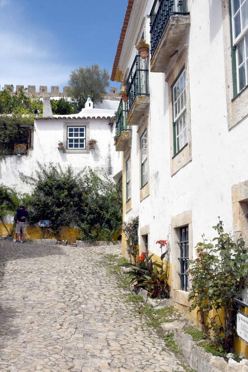 BIDOS (Concelho de bidos), 19.08.2019, Blick in eine Nebenstrae der Rua Direita; im Hintergrund ist die Stadtmauer erkennbar