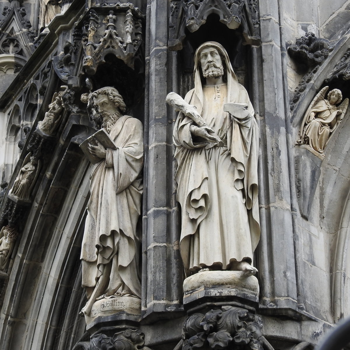 AACHENER DOM-DETAILBILD STEINSKULPTUREN AUSSENFASSADE
Bei meinem letzten Dom-Besuch am 28.4.2017 machte ich dieses Detailbild von Skulpturen des Meisters GTTING an der Auenfassade,das mir doch Rtsel aufgab...
Freundlicherweise konnte mir Dombaumeister H. MAINTZ hier weiterhelfen: Bei der rechten Figur,THADDUS,
fehlen Hand und Rest des Buches,die in den letzten Jahrzehnten stark verwittert waren.Die Bruchstellen
wurden nur begradigt,eine Rekonstruktion in den ursprnglichen Zustand war nicht mehr mglich.
Bei der linken Figur,JACOBUS MINOR,sind die Zehen ebenfalls stark verwittert....
Man sieht schon,ein Dom ist eine ewige Baustelle-sollte er wirklich mal  fertiggestellt  sein,drfte der
Weltuntergang recht nahe sein.....:-)