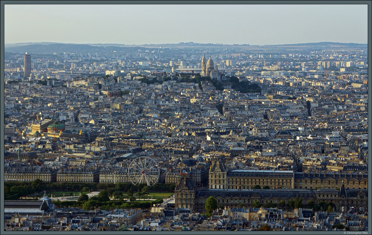 Abendlicher Blick vom Tour Montparnasse: Im Vordergrund ist der Louvre zu sehen. Von der Sonne beleuchtet, sticht auch das Opernhaus am linken Bildrand hervor. ber dem Husermeer erhebt sich im Hintergrund der Montmatre mit der Basilika Sacr-Cur de Montmartre. (18.07.2018)