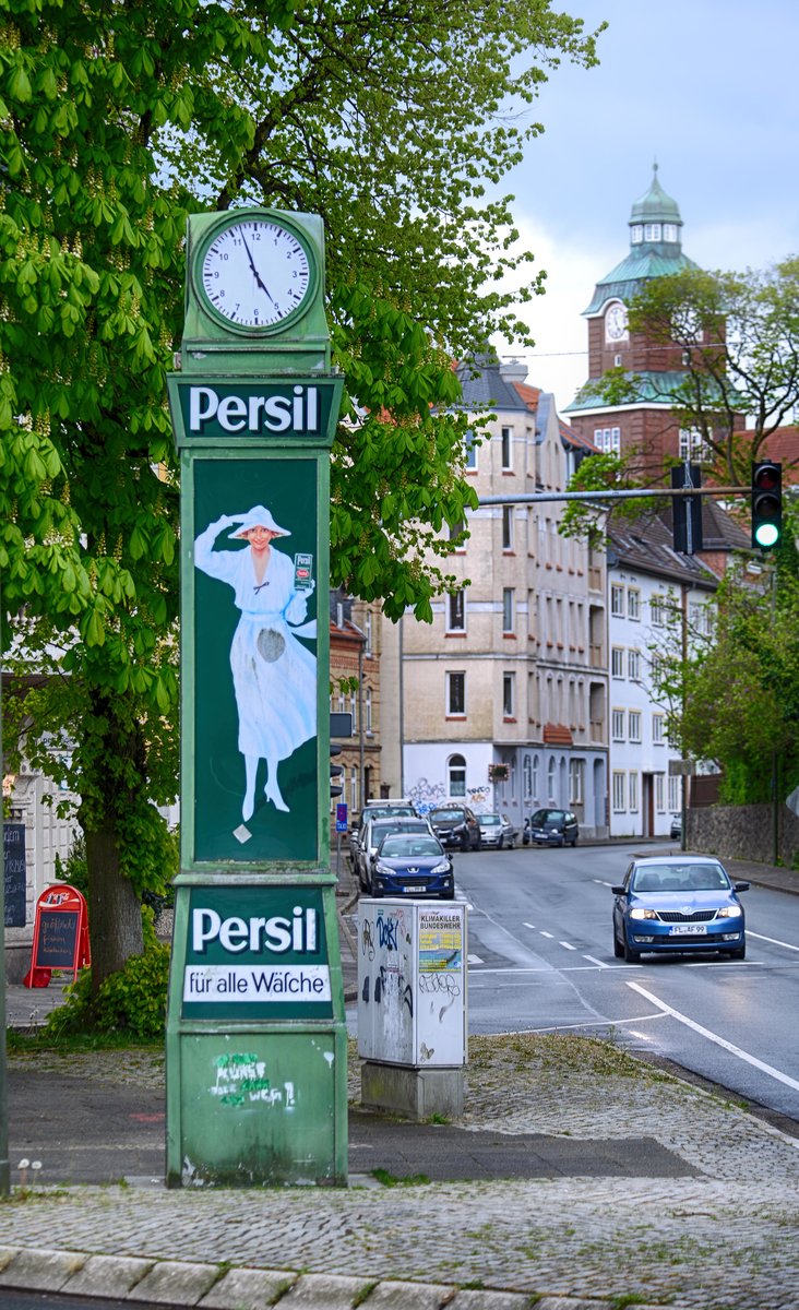 Am Burgplatz in Flensburg neben dem Diakonissenkrankenhaus steht eine Persil-Uhr. Im Hintergrund ist der Turm des Alten Gymnasiums zu sehen. Aufnahme: 2. Mai 2020.