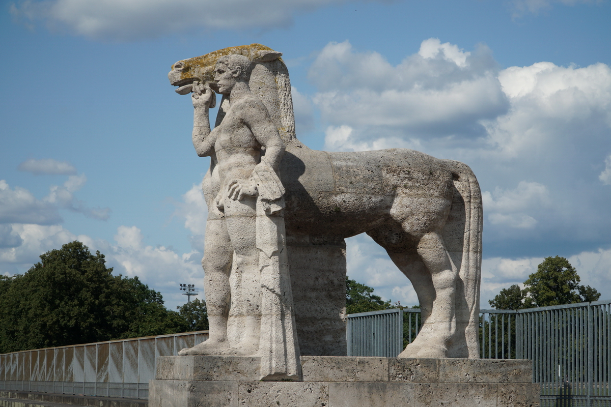 Am bergang vom Olympiastadion zum Maifeld stehen zwei Skulpturen  Rossefhrer  von Joseph Wackerle. Die Skulpturen aus Gauinger Travertin (Swasserkalkstein aus dem Landkreis Reutlingen in Baden-Wrttemberg) wurden vor Ort vom Knstler aus einem groen Steinquader herausgearbeitet. Foto: Sommer, 2019
19.02.2020 Theodor F.