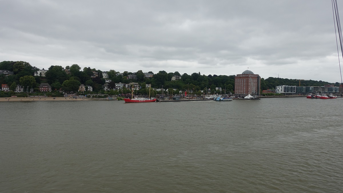 an der Elbe am 14.7.2019: Hamburg, Blick auf velgnne (links) mit dem vielgenutzten Strand, in der Mitte der Fhrschiffanleger Neumhlen/velgnne mit dem Museumshafen  und Neumhlen (rechts) mit der Seniorenresidenz „Augustinum“ (frher Union-Khlhaus), anschlieend der Schlepperponton Neumhlen,  Foto von Bord der CAP SAN DIEGO /  