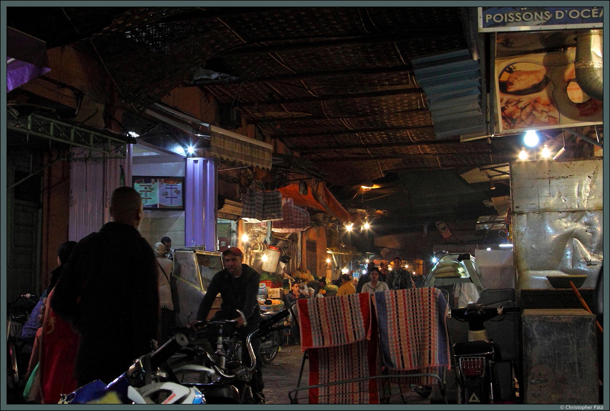 Auch abends herrscht in den Souks von Marrakesch ein dichtes Gedränge. Viele Bäckereien, Fleischereien, Gewürzhändler, Garküchen und kleine Läden reihen sich entlang der schmalen Gasse aneinander. Dieser Souk nahe dem Stadttor Bab Doukkala wird vor allem von Einheimischen genutzt. (Marrakesch, 18.11.2015)