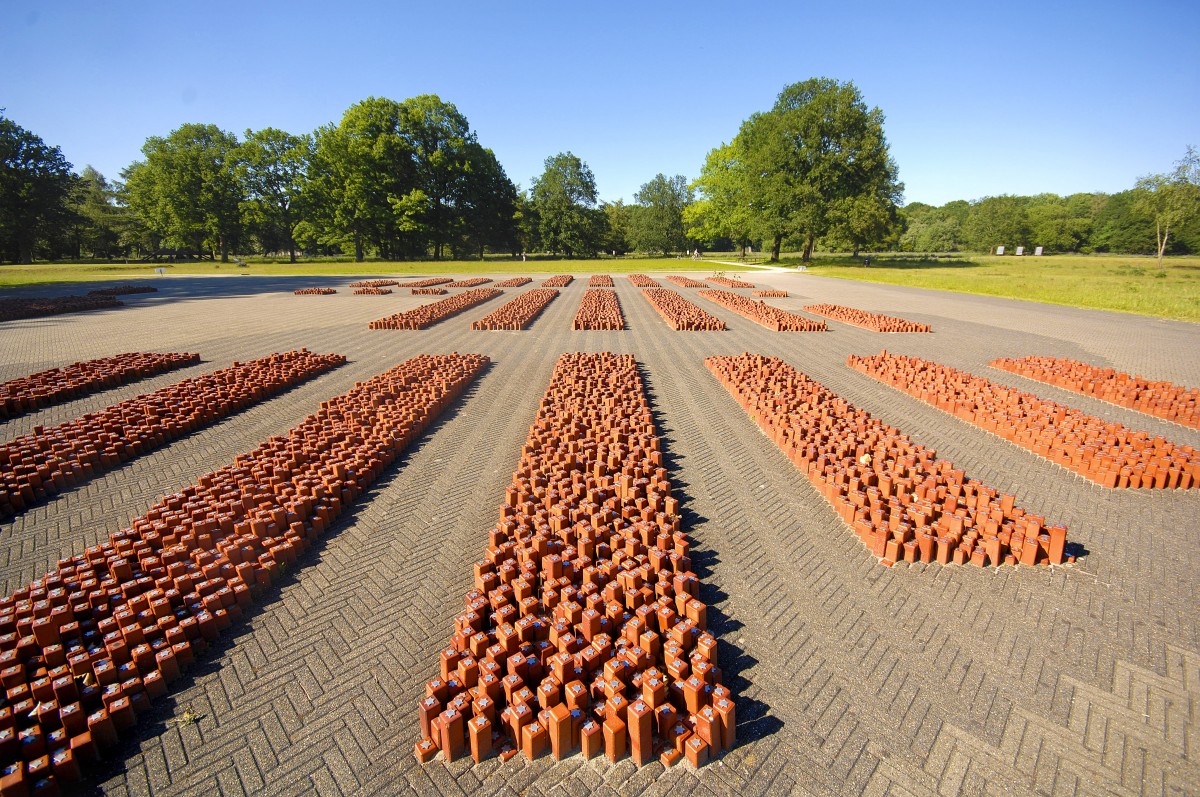 Auf dem ehemaligen Appellplatz im Durchgangslager Westerbork in den Niederlanden befindet sich das Monument Die 102.000 Steine. Auf dem Groteil der Steine sind Davidsterne angebracht, die symbolisch fr die Jdischen Opfer stehen. Auf etwa 200 Steinen ist eine Flamme zu finden. Diese Steine stehen fr die Roma und Sinti, die von Westerbork aus weiter deportiert wurden. Die Steine, auf denen kein Symbol befestigt ist, stehen fr die Widerstandskmpfer, die von Westerbork aus weiter deportiert wurden. Das Besondere des Monuments ist, dass die Steine aus der Vogelperspektive eine Kartographie des Gebiets der Niederlande widerspiegeln.
Aufnahme: Mai 2011.